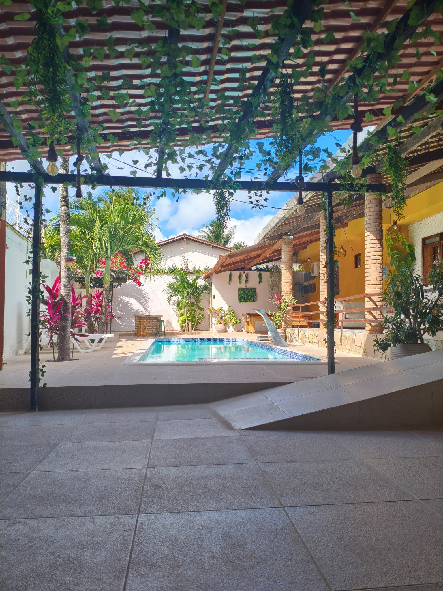 Piscina do Studio29 vista do pátio sombreado com trepadeiras e coluna de tijolo