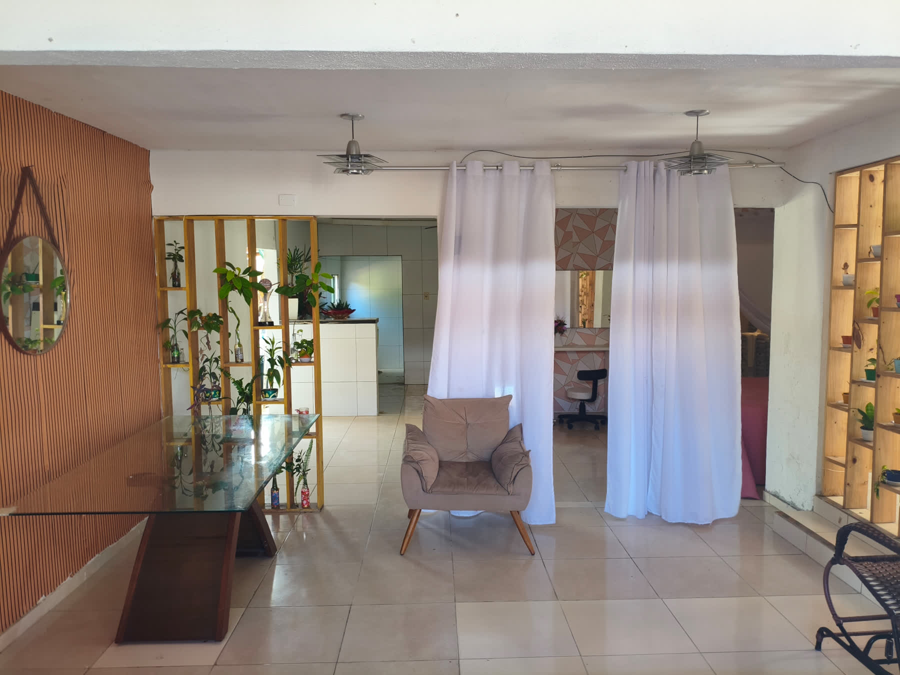 Ambiente interno do Studio29 com poltrona, estantes de plantas e cortinas claras
