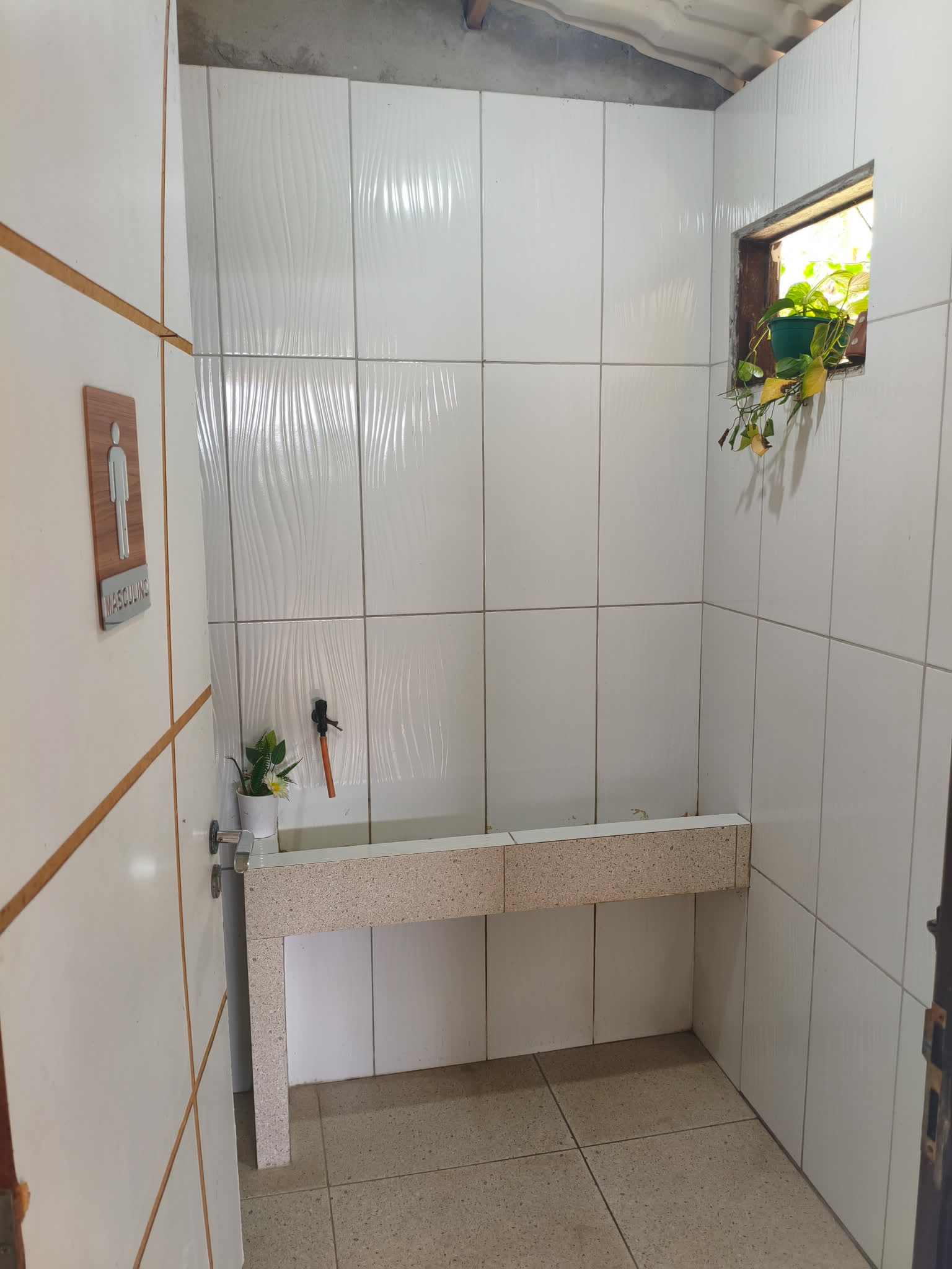 Banheiro masculino do Studio29 com azulejos brancos e bancada de granito