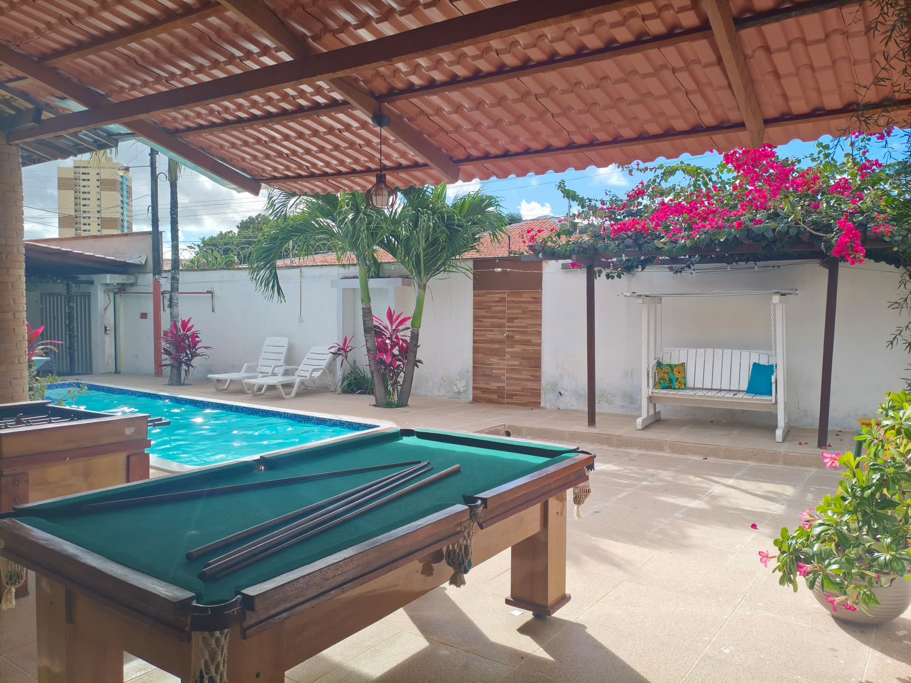 Piscina do Studio29 com sinuca em primeiro plano e balanço de madeira ao fundo