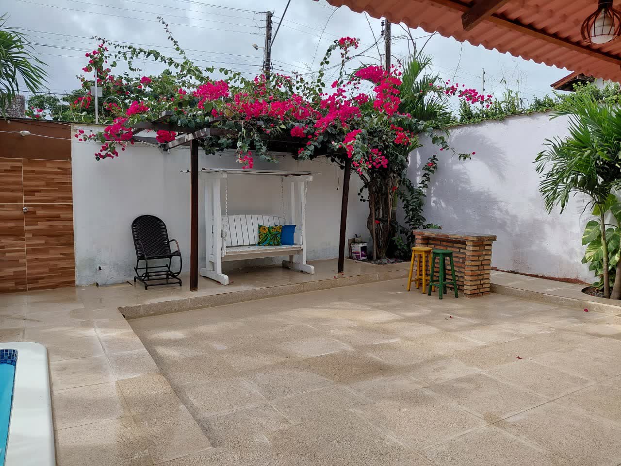 Espaço ao lado da piscina do Studio29 com balanço branco sob pergolado florido
